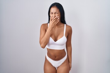 Hispanic woman wearing lingerie bored yawning tired covering mouth with hand. restless and...