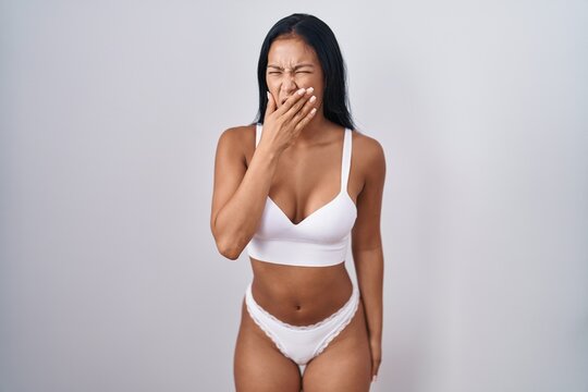 Hispanic woman wearing lingerie bored yawning tired covering mouth with hand. restless and sleepiness.