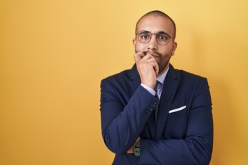 Hispanic man with beard wearing suit and tie looking stressed and nervous with hands on mouth...
