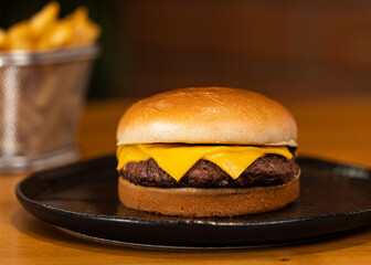 Cheeseburguer com simples com batata frita em segundo plano