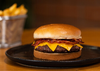 Cheeseburguer com bacon simples com batata frita ao fundo