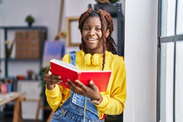 African american woman artist reading book standing at art studio