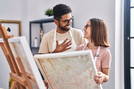 Man and woman artists smiling confident looking draw at art studio