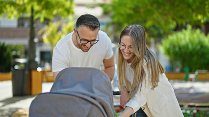 Family of three walking with a baby cart at the park