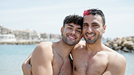 Obraz premium Two men tourist couple smiling confident hugging each other at beach