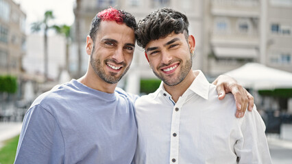 Two men couple smiling confident hugging each other at street