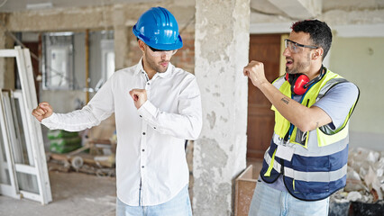 Two men builder and architect smiling confident dancing at construction site