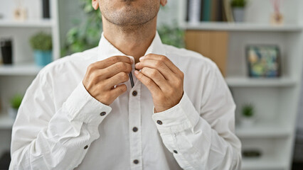 Determined young hispanic man seriously concentrating on success, attired in elegant shirt,...
