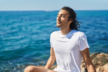 Fototapeta premium Young hispanic man breathing with closed eyes at seaside