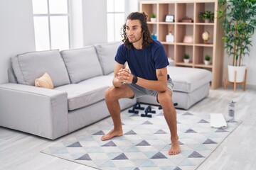 Young hispanic man training yoga at home