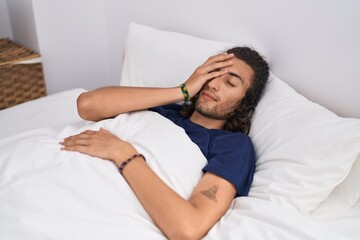 Young hispanic man lying on bed tired at bedroom