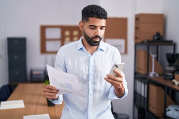 Young arab man business worker using smartphone reading document at office