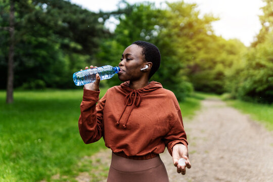 African American woman jogger drinking water hydrating in morning time.