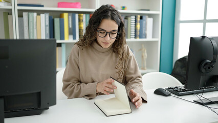 Young beautiful hispanic woman student reading book at library university