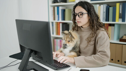 Young hispanic woman with dog student using computer studying at library university