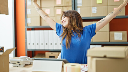 Young beautiful hispanic woman ecommerce business worker stretching arms relaxing at office