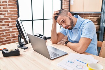 Young latin man ecommerce business worker stressed using laptop at office