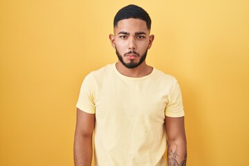 Young hispanic man standing over yellow background depressed and worry for distress, crying angry and afraid. sad expression.