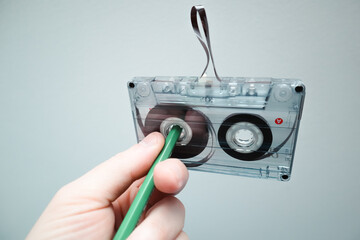 Classic cassette tape. Hand rewinding a cassette tape with a pen. 90's concepts. Vintage audio...