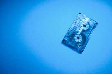 Transparent audio cassette tape photo on blue background. Place for text.