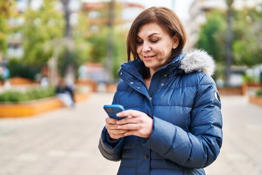 Middle age woman smiling confident using smartphone at park