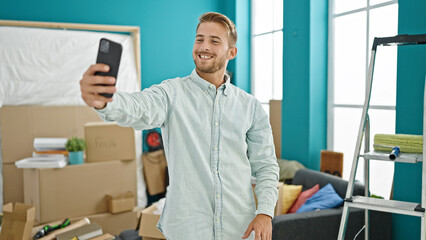 Young caucasian man make selfie by smartphone smiling at new home