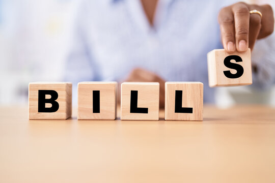 Black woman holding cubes with bills word on the table