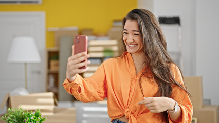 Young beautiful hispanic woman having video call standing at new home