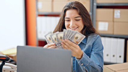Young beautiful hispanic woman ecommerce business worker counting dollars smiling at office