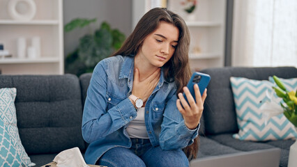 Obraz premium Young beautiful hispanic woman using smartphone having online medical consultation at home