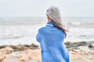 Middle age grey-haired woman standing on back view at seaside