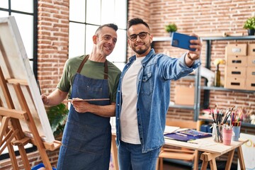 Two men artists smiling confident make selfie by smartphone at art studio