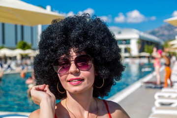 Bright cheerful girl animator near the pool, black lush curly curly hair and sunglasses.