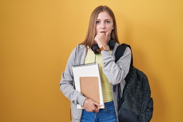 Young caucasian woman wearing student backpack and holding books thinking worried about a question, concerned and nervous with hand on chin