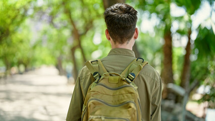 Fototapeta na wymiar Young hispanic man tourist wearing backpack standing backwards at park