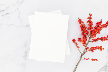 Empty blank white magazine cover mock up and branch with red berries on white marble table background.