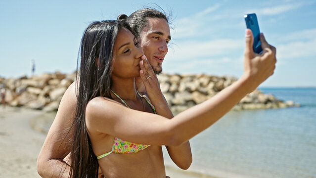 Man and woman tourist couple standing together make selfie by smartphone at beach