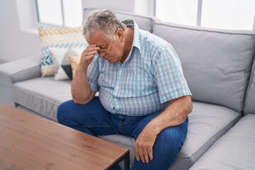 Fototapeta premium Middle age grey-haired man stressed sitting on sofa at home