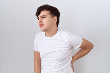 Young non binary man wearing casual white t shirt suffering of backache, touching back with hand, muscular pain