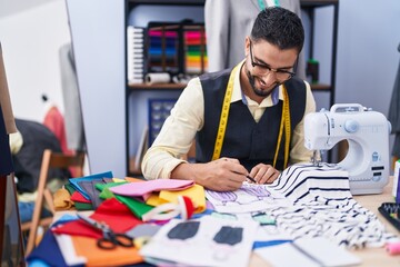 Young arab man tailor smiling confident drawing on notebook at clothing factory