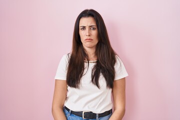 Fototapeta premium Young brunette woman standing over pink background looking sleepy and tired, exhausted for fatigue and hangover, lazy eyes in the morning.