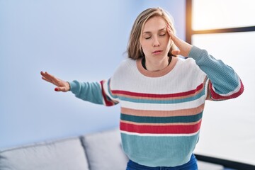 Young blonde woman suffering dizzy standing at home