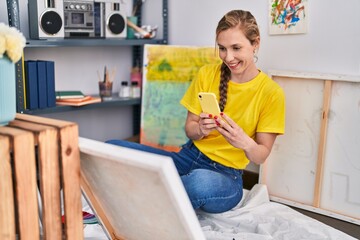 Young blonde woman artist make photo to draw by smartphone at art studio