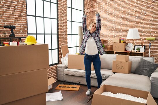 Young blonde woman smiling confident stretching arms at new home
