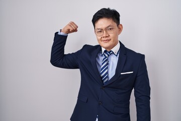 Young asian man wearing business suit and tie strong person showing arm muscle, confident and proud of power