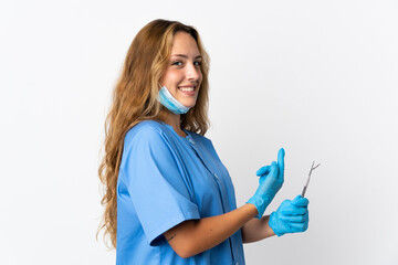 Woman dentist holding tools isolated on white background pointing back