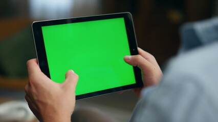 Gamer hands playing mockup tablet at room. Closeup man tapping greenscreen pad