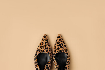 Leopard print shoes on beige background. Fashion spring, summer or autumn outfit. Women's stylish and elegant clothes with accessory.  Flat lay, top view, overhead.