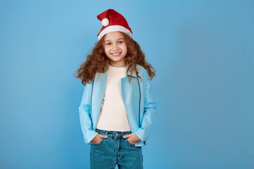 Little smiling afro-american girl with Santa hat on blue background.