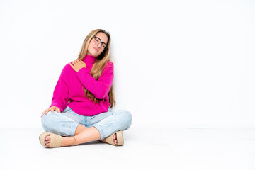 Young caucasian woman sitting on the floor isolated on white background suffering from pain in shoulder for having made an effort